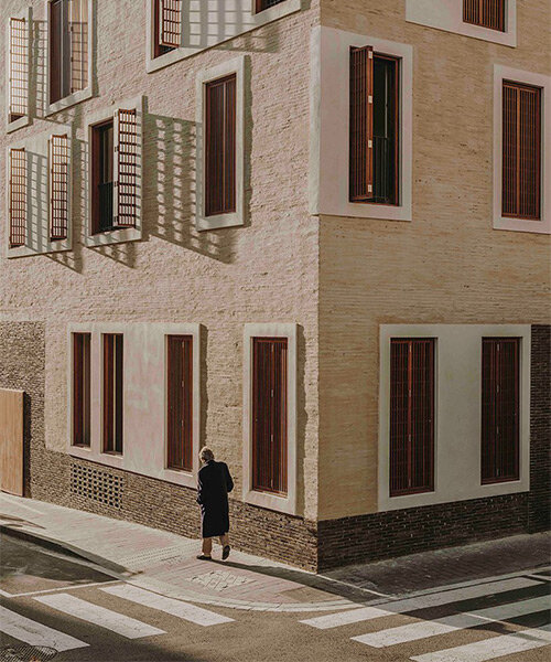 fachadas texturizadas, persianas de madera y rodapiés que detallan la forma de un edificio de viviendas múltiples en barcelona