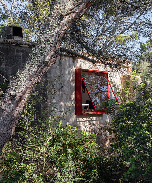 ventana roja sobresale de la reforma del tradicional refugio de piedra de mariana de delás en mallorca