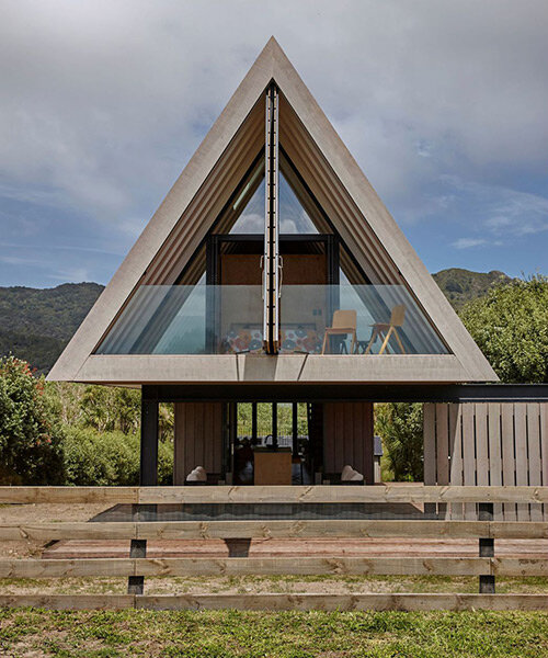 una cabaña en forma de 'A' en nueva zelanda respeta el paisaje costero local y la cultura maorí