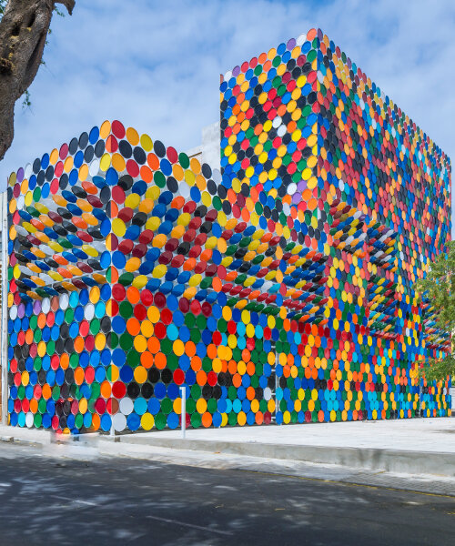 las tapas reversibles de barriles de transporte alegran la fachada arco iris en un edificio del centro nacional de arte de cabo verde
