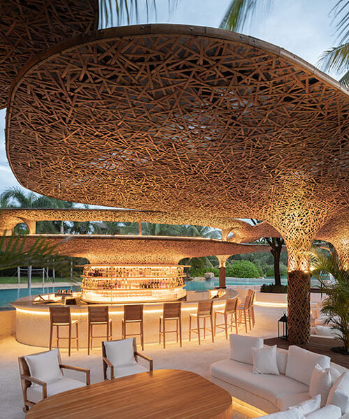 un dosel de estructuras tejidas de bambú se agrupa sobre el club de playa de un resort en medio de los cocotales de china