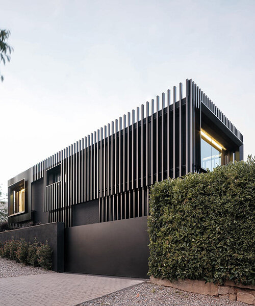 una envolvente monocromática de listones negros de acero moderniza una vivienda unifamiliar en barcelona