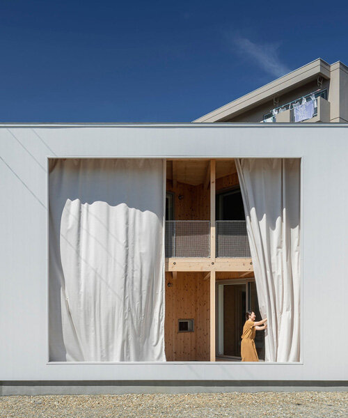 una gran cortina transforma el interior de una casa japonesa en una terraza semiexterna