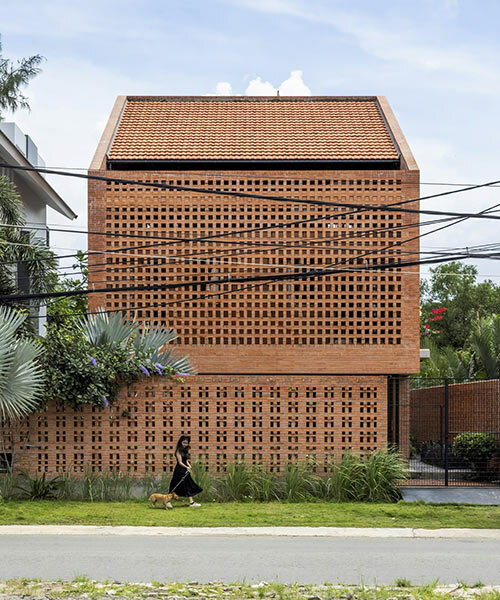 una fachada de ladrillo perforado envuelve la casa nhà bè de tropical space en vietnam