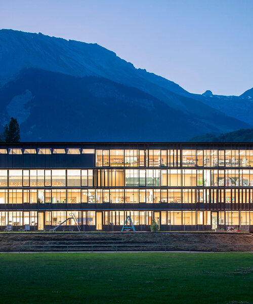la fachada con celosías de la ampliación de una escuela se abre por completo al paisaje alpino suizo